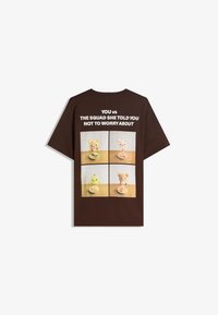 Braunes Baumwoll-T-Shirt mit vier Feldern von Spielzeug-Tieren mit verspielten Gesichtsausdrücken, begleitet von weißem Text in fetter Schrift.