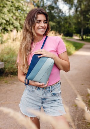 Compact bag in shades of navy and blue, featuring horizontal stripes. Made of smooth material with a shoulder strap and logo detail.