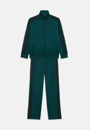 Träningsoverall i mörkgrön med svarta ränder, zip-up jacka och byxor, med sidofickor, ribbade ärmslut och logotypdetalj på bröstet.