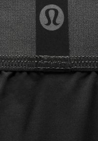 Zwart sportief stof met een gestructureerd oppervlak, een contrasterende gladde band en een rond logo. De naden tonen gedetailleerd stikwerk.