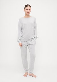 Top cinza claro, de mangas longas, com decote redondo; calças jogger leves coordenadas, com punhos elásticos. Textura suave, ajuste descontraído.