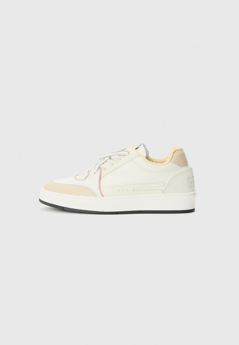 Sneaker bianchi e verde chiaro con una finitura testurizzata, dotate di lacci grigi, colletto imbottito e una suola nera spessa. Accenti di cuciture rosse.
