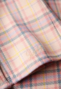 Plaid fabric in pastel hues of pink, blue, and yellow, featuring a textured finish. Embroidered "Sweety" detail in a subtle font.