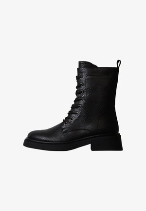 Botte de combat noire mi-mollet en cuir texturé, lacets à l'avant, languette à l'arrière et semelle épaisse à talon bas.