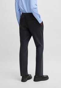 Black, elastic waistband trousers with a straight-leg design. The fabric is smooth, featuring side pockets and a tailored fit.