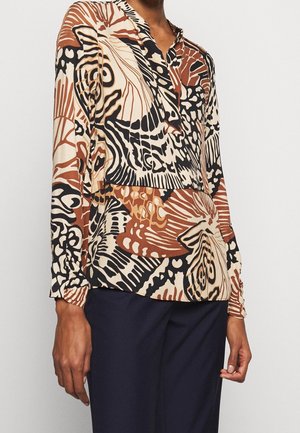 Blouse à manches longues en beige, marron et noir avec des motifs floraux abstraits. Encolure à découpe, tissu texturé et poignets ajustés.