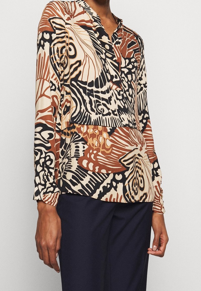 Blusa a maniche lunghe in beige, marrone e nero con motivi floreali astratti. Collo a V, tessuto testurizzato e polsini aderenti.