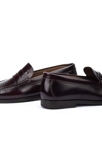 Mocasines de cuero burdeos con un diseño cosido, tacón plano y una correa decorativa en la parte delantera. Textura suave con un acabado pulido.