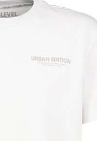 Weißes Baumwoll-T-Shirt mit runden Halsausschnitt und kurzen Ärmeln. In hellbrauner Schrift steht auf der Brust "URBAN EDITION" neben Markendetails.