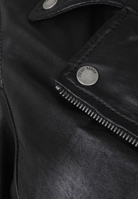 Czarna skórzana kurtka z przednim zamkiem błyskawicznym, zatrzaskami na guziki oraz teksturowanym wykończeniem. Metka z napisem "Freaky Hanoch".