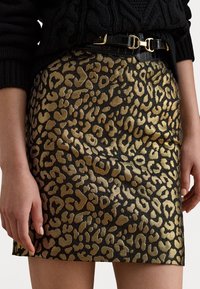 Ränder med leopardmönster på en kjol med en metallisk guld- och svart design, texturerad tyg och ett svart läderbälte med guldhardware.