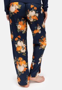 Bloemenbroek met een marineblauwe achtergrond, versierd met oranje pompoenen en witte bloemen. Zachte stof met zijsplitsingen bij de enkels.