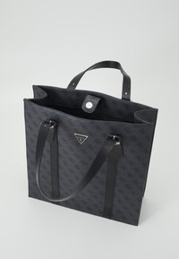 Svart tygkasse med en texturerad mönster, som har läderhandtag, knäppstängning och en liten logotypaccent på framsidan.