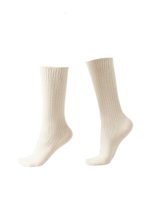 Paire de chaussettes côtelées beige mi-mollet présentées debout avec une chaussette légèrement pliée à la cheville sur fond blanc.