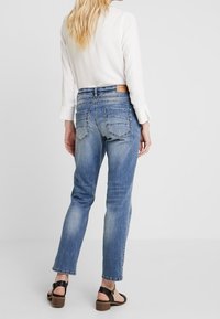 Ljusblå denimjeans med avslappnad passform, med bakfickor, subtila blekningar och raka ben. Bar tillsammans med en vit långärmad skjorta.