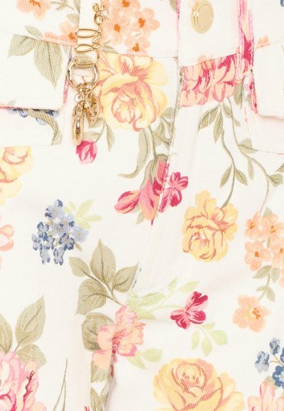 Tessuto bianco con motivo floreale composto da fiori gialli, rosa, rossi e blu e foglie verdi, con ciondoli dorati a forma di portachiavi attaccati a un passante della cintura.