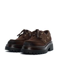 Scarpe in suede marrone con una robusta suola in gomma nera, dotate di occhielli dorati e design con lacci, con una finitura liscia e dettagli testurizzati.