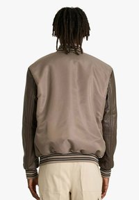 Giacca bomber marrone con finitura satinata, maniche in pelle, polsini a coste e cintura a righe. Vista posteriore che mostra un design semplice.