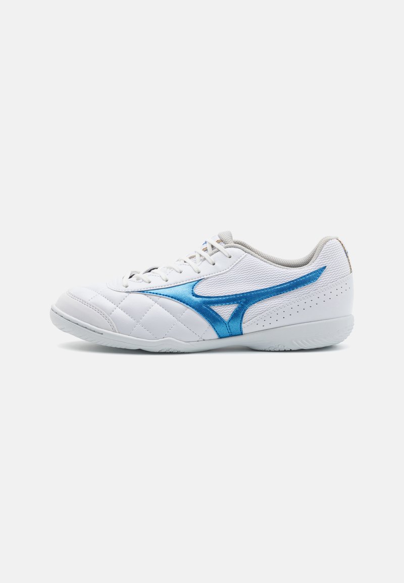 Scarpa sportiva bianca con texture trapuntata, dettagli blu, tomaia in rete e suola in gomma. Presenta un design con lacci e fori per la traspirabilità.