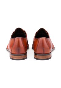 Un paio di scarpe eleganti in pelle marrone lucida con tacchi a strati in legno, viste da dietro su uno sfondo bianco.