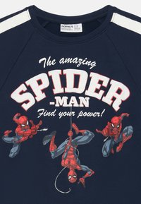 Camiseta de algodón color azul marino con tres gráficos de Spider-Man y el texto "¡El asombroso SPIDER-MAN Encuentra tu poder!" en letras blancas en negrita.