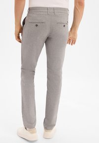 Lichtgrijze broek van een gestructureerde stof, slim fit, met twee achterzakken met knopen en een subtiel visgraatpatroon.