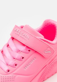 Rózsaszín Skechers cipők sima szintetikus felső résszel, fűzős kialakítással, állítható pánttal és perforált díszítéssel a légáteresztés érdekében.
