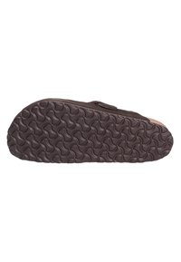 Boven een bruine suède pantoffel met een gestructureerde bruine rubberen zool, voorzien van een golfpatroon voor grip en een enkele verstelbare riem voor een goede pasvorm.