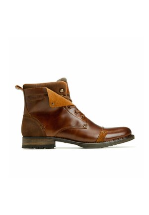 Bottine en cuir marron avec col en suède doux replié, fermeture à lacets à l’avant et petit talon empilé sur fond blanc.
