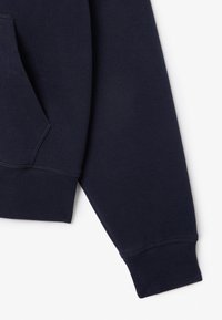 Donkerblauwe sweatshirt met een gestructureerd oppervlak, voorzien van een kangoeroezak en geribbelde boorden. Het ontwerp heeft een klassieke pasvorm met zijnaden.