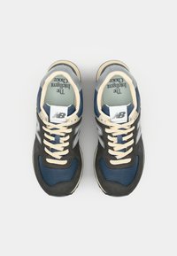Zapatillas deportivas en azul y gris con parte superior de malla y ante, cordones color crema y un logo blanco. Presentan una superficie texturizada y un collar acolchado.