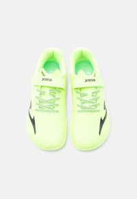Ζευγάρι αθλητικά παπούτσια νέον πράσινου χρώματος με μαύρο λογότυπο, κορδόνια και λουριά Velcro που εμφ ανίζουν το όνομα της μάρκας "Joma", φωτογραφημένα από πάνω.