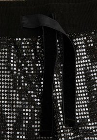 Czarna tkanina z cekinami o teksturowanym wykończeniu, z czarnym welwetowym sznurkiem w talii, prezentująca lśniący wzór.