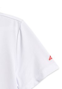 Chemise blanche en coton à manches courtes avec coutures visibles et texte rouge partiellement imprimé sur la manche, sur fond blanc.