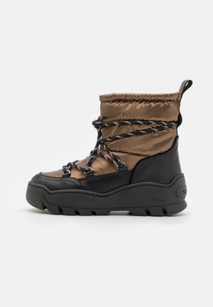 Botte d'hiver matelassée marron avec semelle noire, bordure noire et lacets réfléchissants noir et blanc enroulés autour de la cheville.