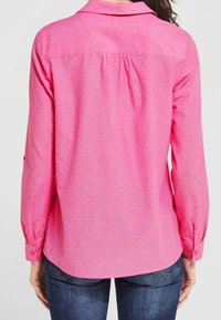 Camicia a maniche lunghe rosa realizzata in tessuto morbido, con un motivo sottile, dettagli con bottoni sulle maniche e un design del colletto classico.