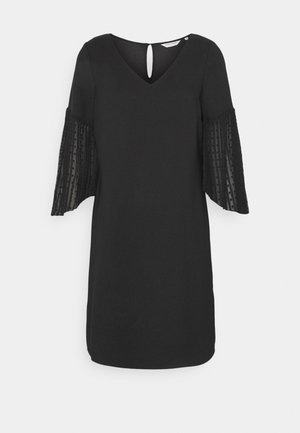 Robe noire longueur genoux avec encolure en V, fermeture au dos par bouton avec ouverture en forme de goutte, et manches cloche transparentes ornées de motifs de rayures verticales et de points.