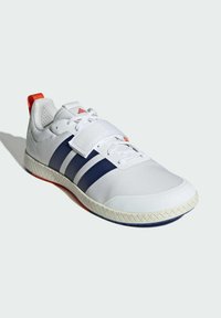 Biele športové topánky s námorníckymi pruhmi, textúrovaný zvršok, gumová podrážka, oranžový jazyk a šnurovanie, s pripojeným suchým zipsom.