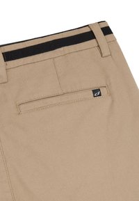 Khaki spodnie o gładkiej fakturze, z czarnym paskiem wzdłuż talii oraz tylną kieszenią z małą czarną naszywką logo.