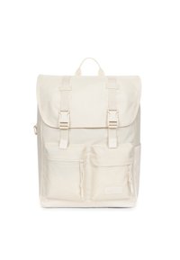 Zaino in tessuto off-white con chiusura a patta, due tasche frontali, spallacci regolabili e maniglia superiore. Presenta un design e dettagli minimalisti.