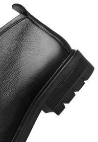 Schwarze Lederknöchelstiefel mit strukturiertem Finish, abgerundeter Zehenpartie, robustem Sohlenprofil mit ausgeprägtem Profil und einem Ziehhilfe an der Rückseite.