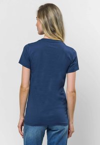 Sötétkék pamut póló, rövid ujjú, kerek nyakkivágással, sima textúrával és testhezálló fazonnal. Hátul nézet minimális dekorációval.