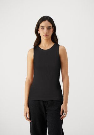 Top negru fără mâneci, cu decolteu rotund, având un design ajustat care se extinde până la șolduri. Asortat cu pantaloni negri, largi.