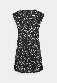 Robe noire sans manches avec petit motif floral blanc et coupe légèrement évasée sur un fond uni clair.