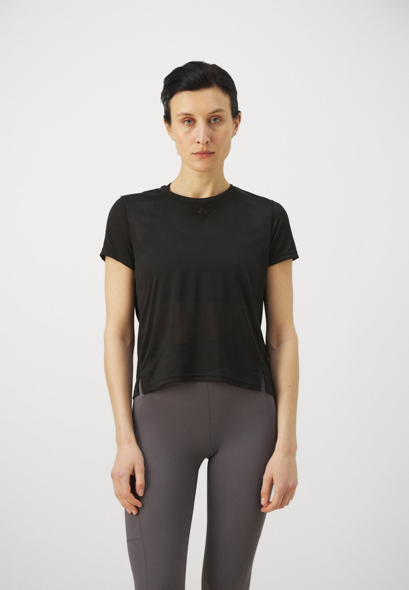 Svart kortermet treningstopp, lett materiale, rund halslinning, sidespalter. Kombinert med tettsittende, høyt liv grå leggings.