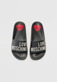 Svarta halkskor med texturerad yta och breda remmar med "LOVE MOSCHINO"-logotyp i vitt och röda hjärtan på varje fotbädd.