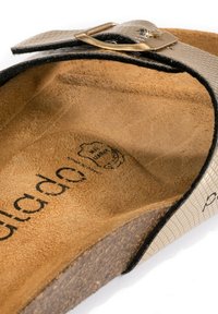 Sandalo con plantare, caratterizzato da una parte superiore sintetica beige texturizzata con contorno nero, suola intermedia in sughero e soletta in suede marrone.
