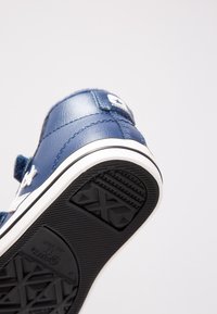 Niebieski skórzany sneakers z rzepem, białym logo w kształcie gwiazdy oraz teksturowaną czarną gumową podeszwą z wzorem diamentowym dla lepszej przyczepności.
