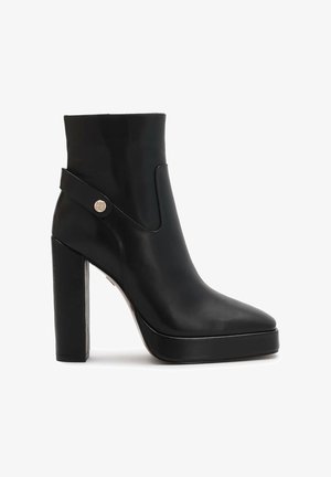 Must musta kõrge kontsaga ankle boot mustast nahast, platvormi sisetald, rihma detail ja kuldne nupukaunistus välist küljel.