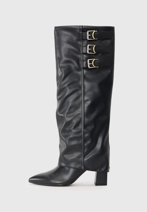 Svart lær knelang støvel med spiss tå, blokkhæl, og tre dekorative spenner på siden. Rynket tekstur gir visuell interesse.